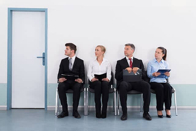 four people waiting outside of a plain door