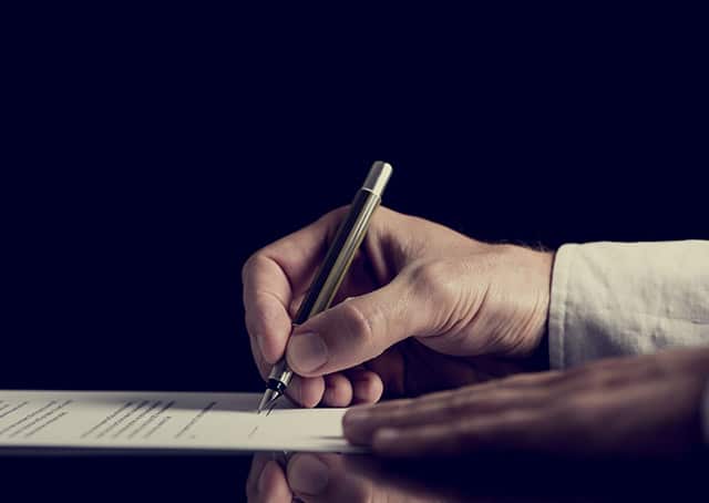 man's hand signing a document